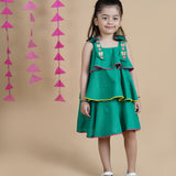 Girl wearing Green Cotton frock which has embroidered straps and layers