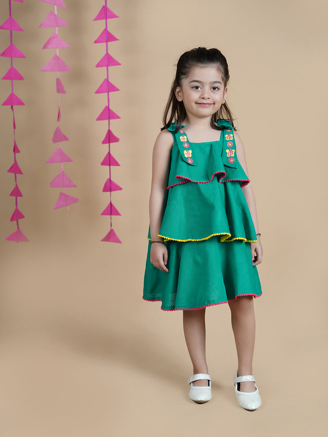 Girl wearing Green Cotton frock which has embroidered straps and layers