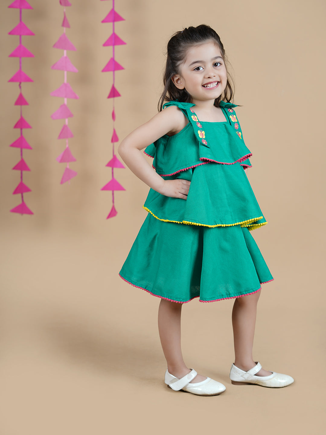 Green Girl wearing Green Cotton frock which has embroidered straps and layers