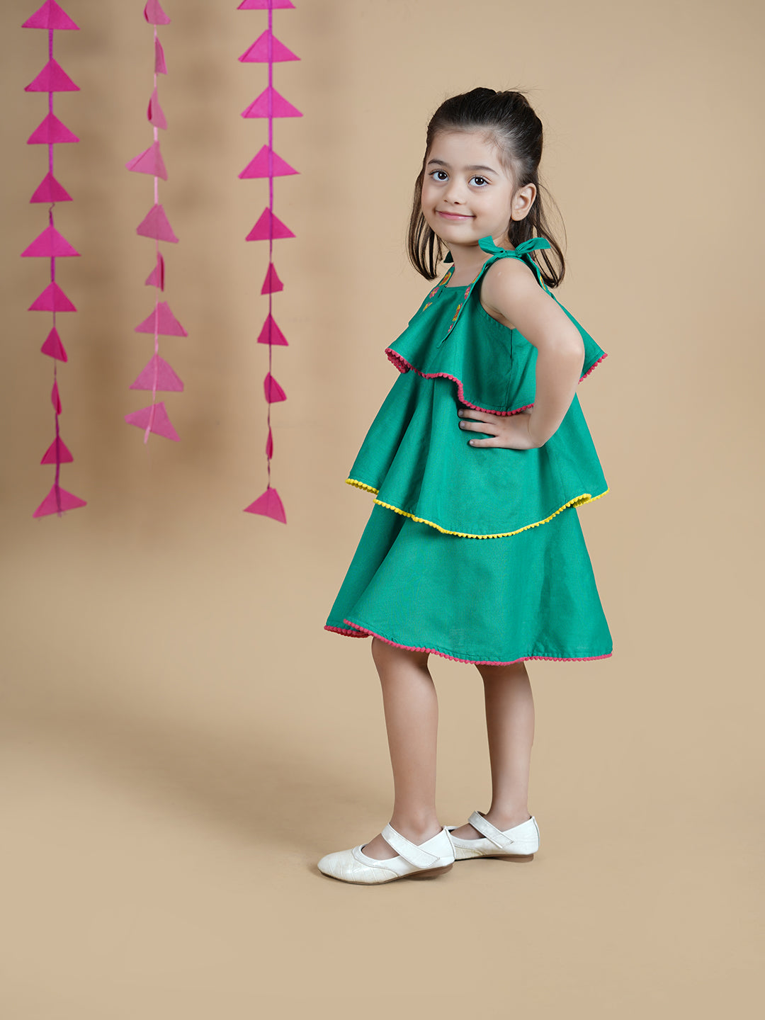 Girl wearing Green Cotton frock which has embroidered straps and layers