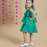 Girl wearing Green Cotton frock which has embroidered straps and layers