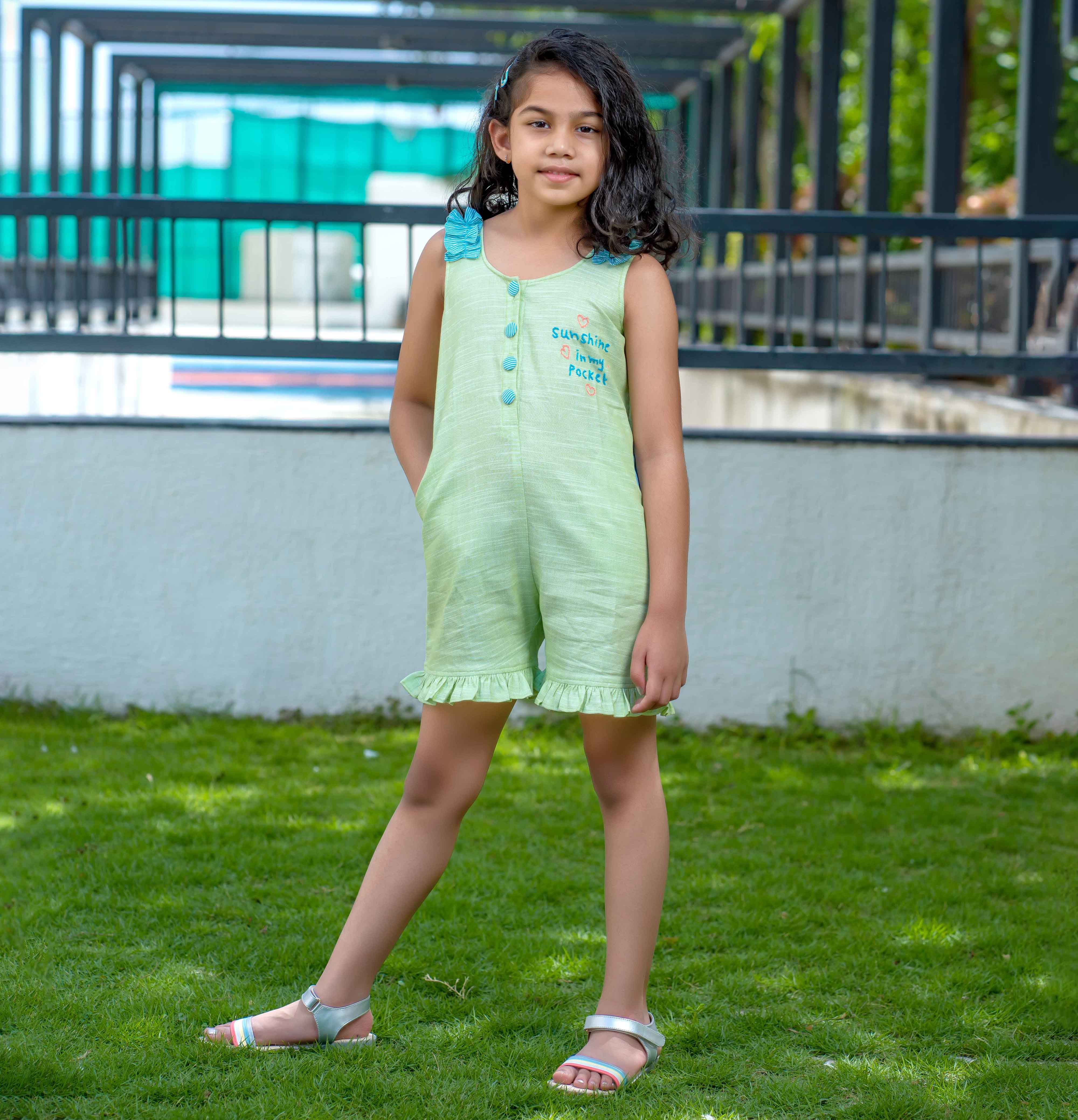 A girl wearing green jumpsuit with Sunshine in my pocket embroided on it