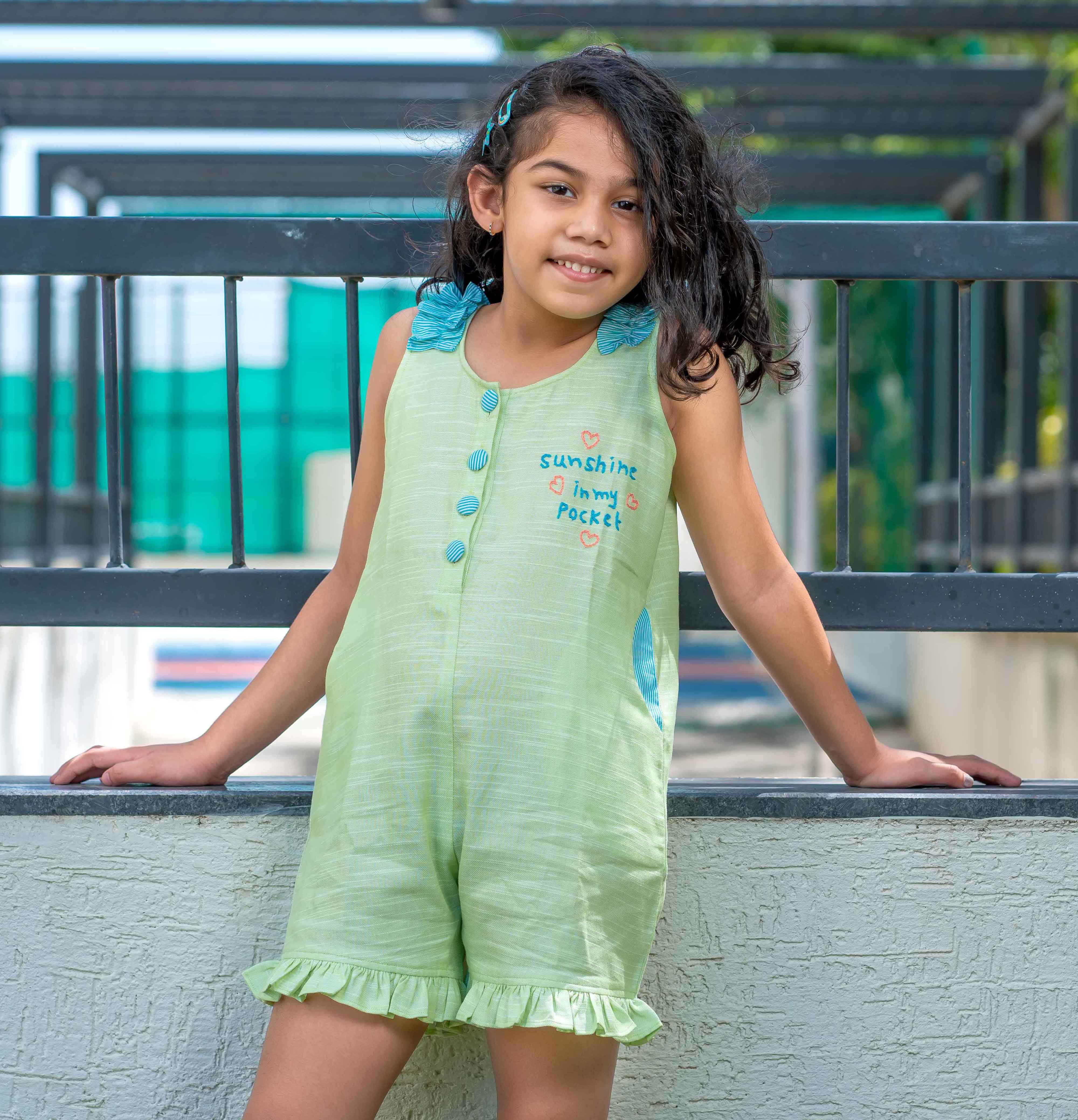 A girl wearing green jumpsuit with Sunshine in my pocket embroided on it