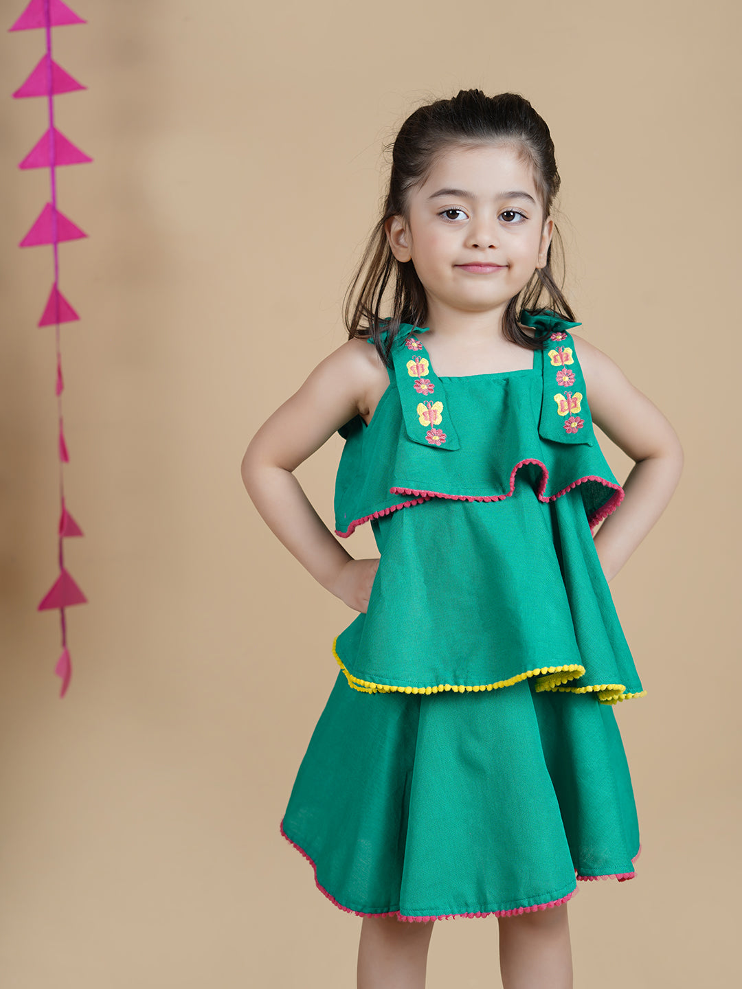 Girl wearing Green Cotton frock which has embroidered straps and layers