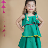 Girl wearing Green Cotton frock which has embroidered straps and layers