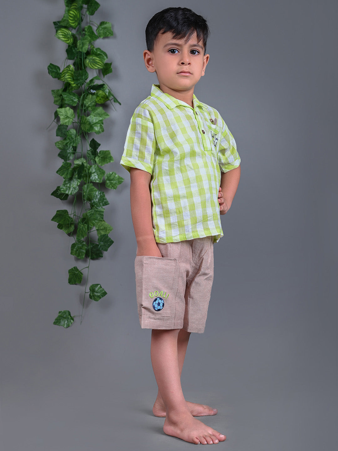 A boy wearing lime green drop shoulders shirt and beige linen shorts