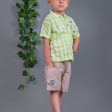 A boy wearing lime green drop shoulders shirt and beige linen shorts