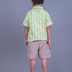 A boy wearing lime green drop shoulders shirt and beige linen shorts