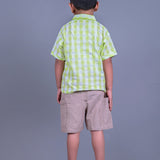 A boy wearing lime green drop shoulders shirt and beige linen shorts