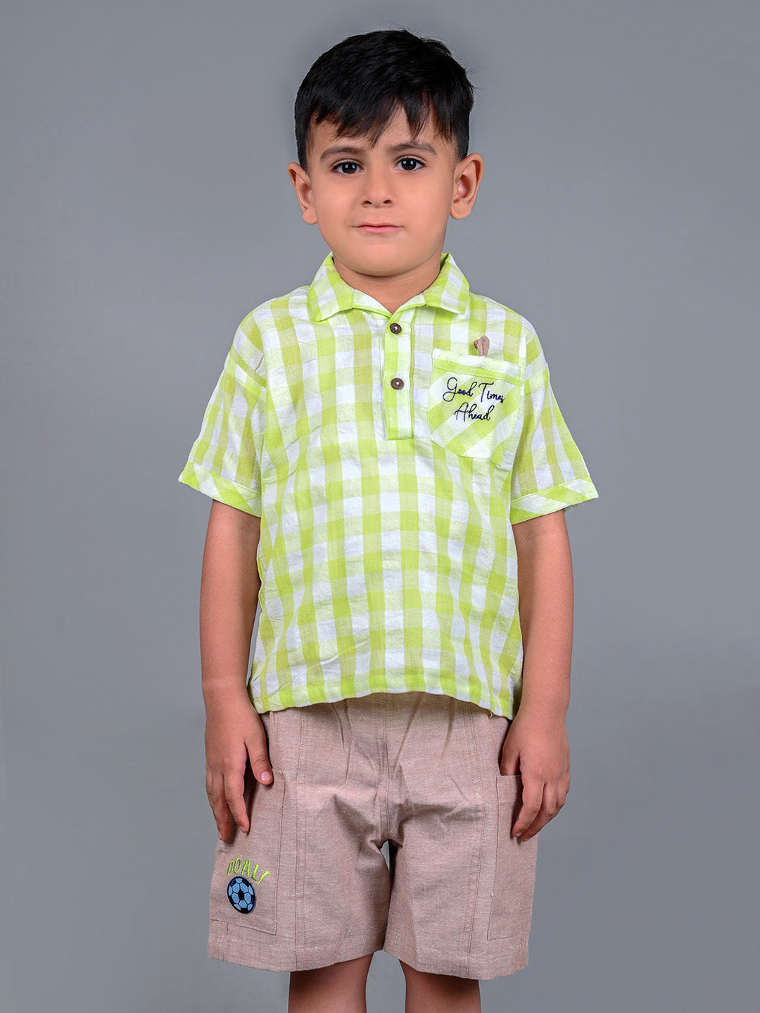 A boy wearing lime green drop shoulders shirt and beige linen shorts