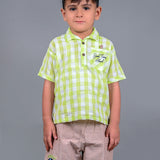 A boy wearing lime green drop shoulders shirt and beige linen shorts