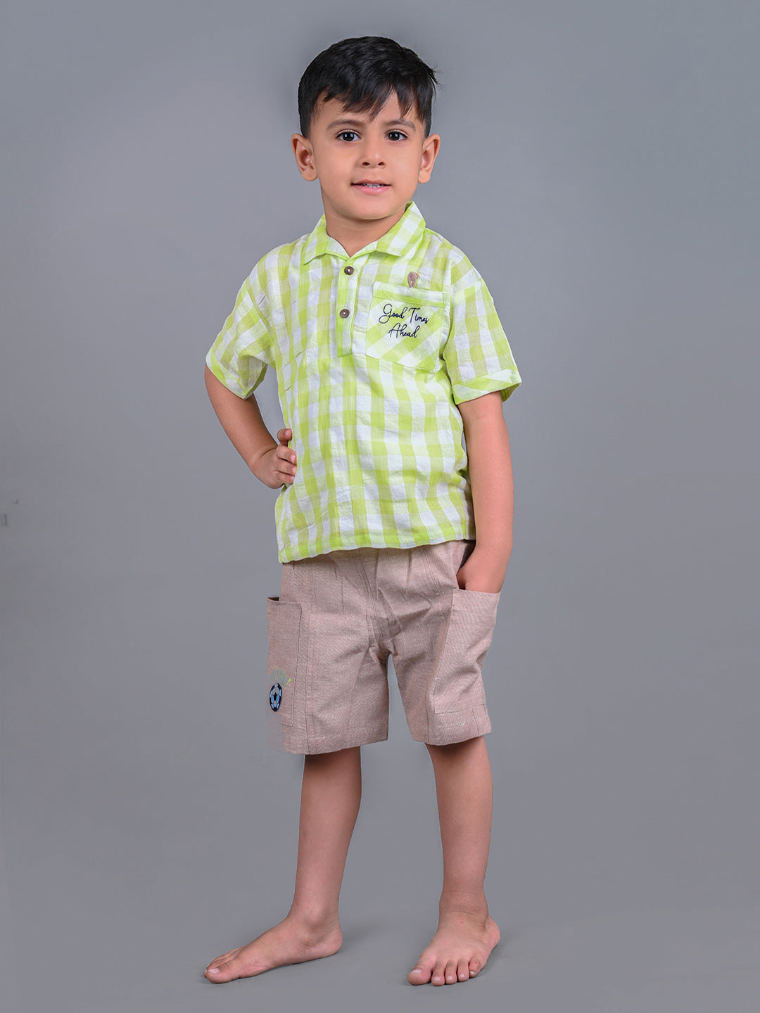 A boy wearing lime green drop shoulders shirt and beige linen shorts