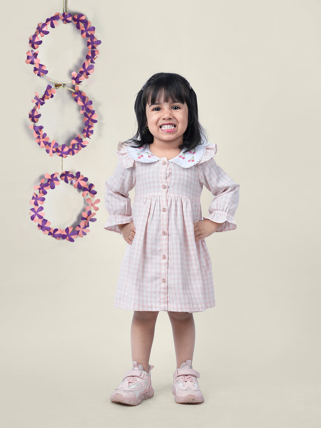 A girl wearing cotton checks gingham frock with cherries embroidered on collar