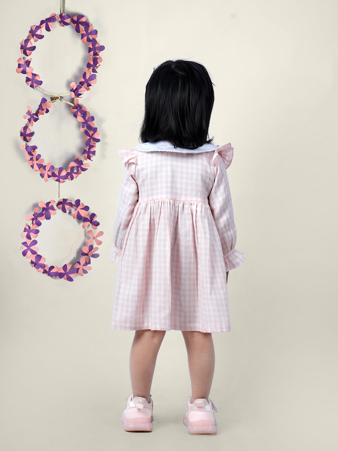 A girl wearing cotton checks gingham frock with cherries embroidered on collar