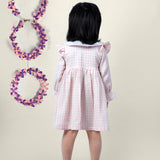 A girl wearing cotton checks gingham frock with cherries embroidered on collar