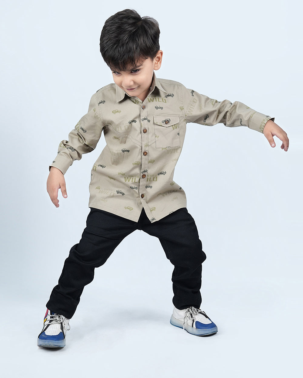 A boy wearing khaki cotton shirt with full sleeves and has cars printed on it