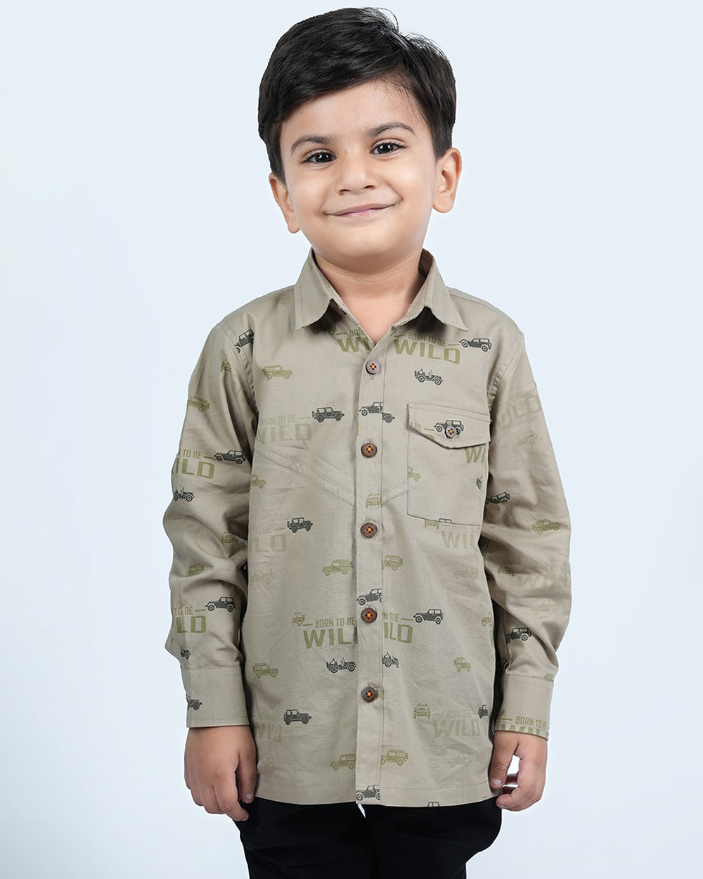 A boy wearing khaki cotton shirt with full sleeves and has cars printed on it