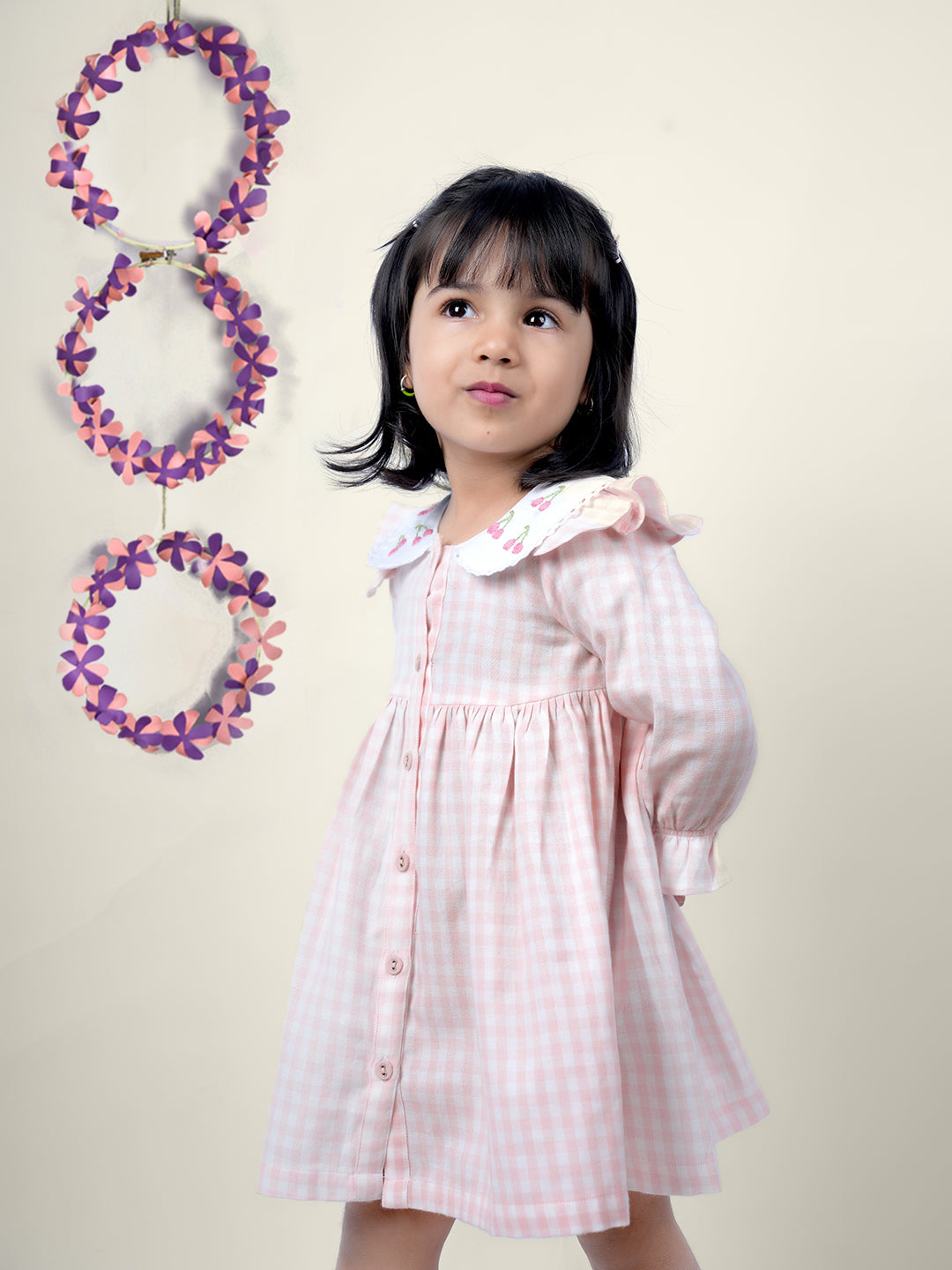 A girl wearing cotton checks gingham frock with cherries embroidered on collar